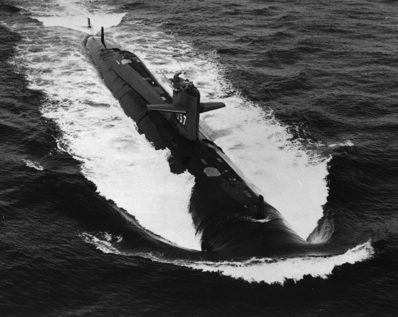 Aerial view of nuclear powered attack submarine USS Tullibee (SSN-597) underway during sea trials in Long Island Sound. Note the vertical fore and aft dorsal fins, which contained sonar gear. Taken circa early October 1960.