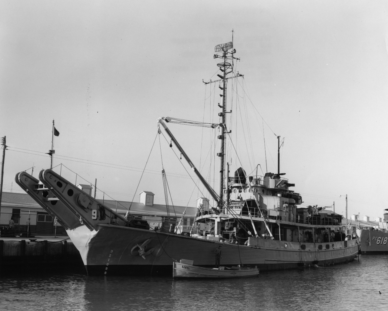Port bow view of net laying ship USS Waxsaw (AN-91) tied up alongside a pier