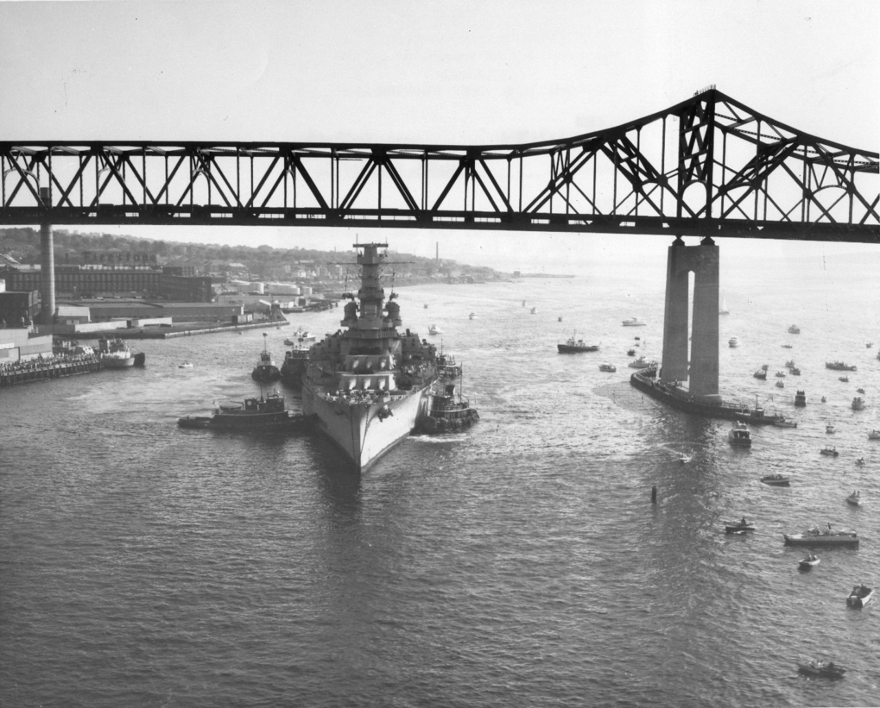 View of ex-USS Massachuetts (BB-59) as tugs maneuver it into position beneath a bridge in Fall River, Massachusetts, to its new home as a museum ship, 12 June 1965.