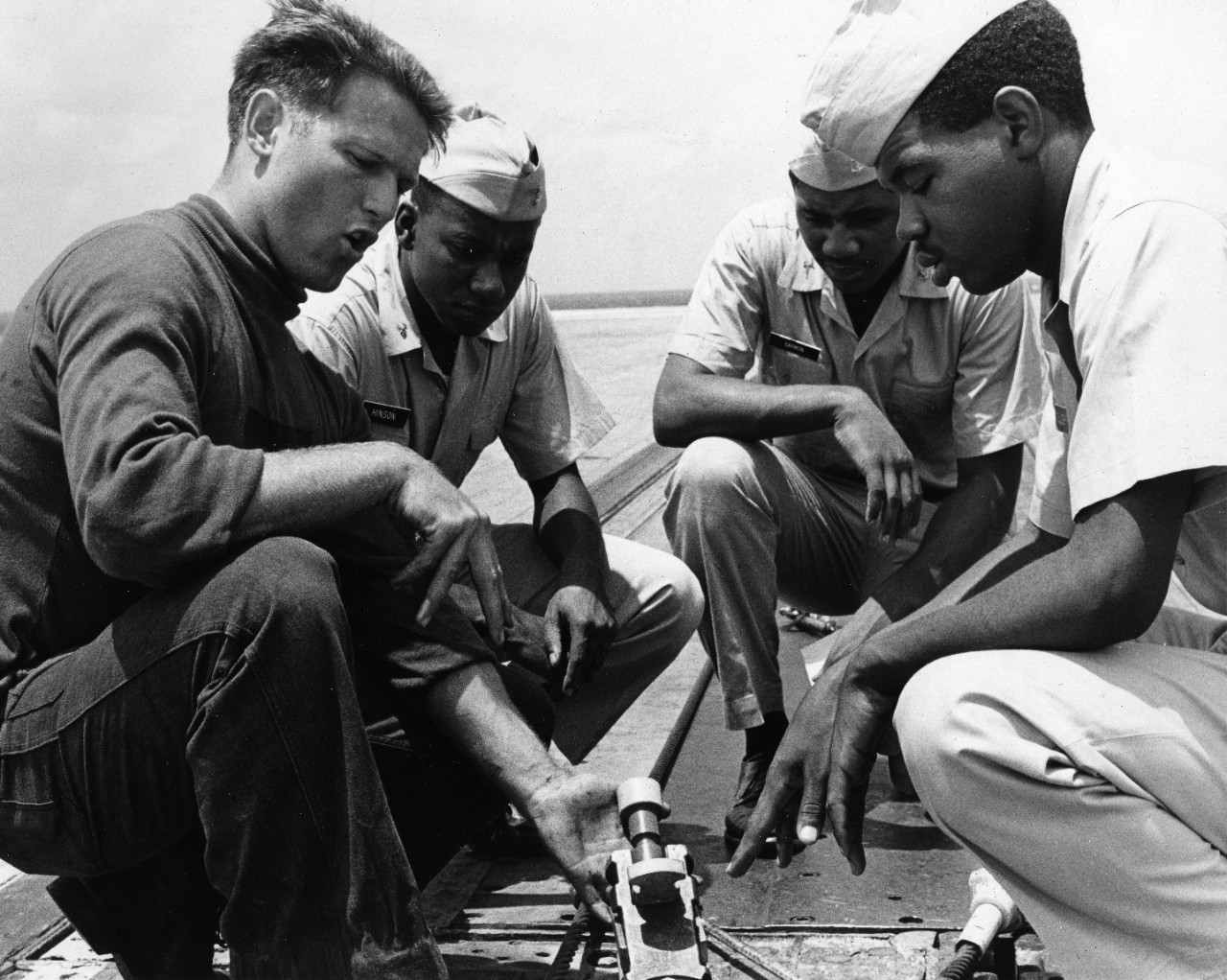 Airman Howard J. Johnson (left) shows a holdback for an F-9 Cougar fighter aircraft to midshipmen from Prairie View A & M College. They are aboard the carrier USS Lexington (CVS-16) for a two week cruise as part of their Navy training.
