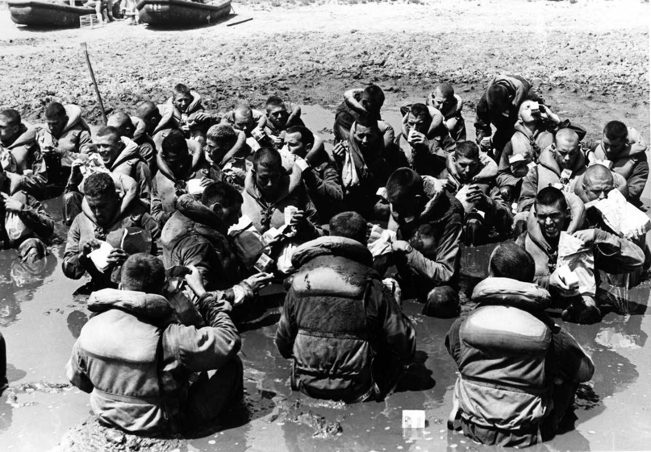 Underwater Demolition Team (UDT) recruits eating lunch in the mud