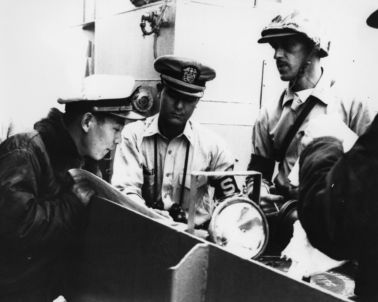 Grade Chujyo Kodo, Japanese Maritime Self Defense Force; Lieutenant Junior Grade Ricard L. Takahashi, USN, attached to the USS Kearsarge (CVS-33); and Captain John Dornan, USMC, Commanding Officer of the Marine Detachment on board the Kearsarge. This LCM is being used to transport water, bread, and medicine to areas flooded by Typhoon Vera.