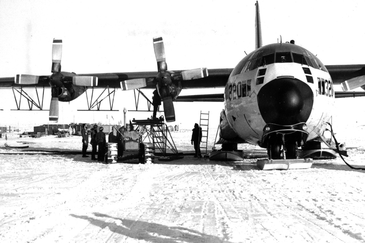 Navy men from Antarctic Development Squadron Six (VXE-6) prepare the ski-equipped LC-130 aircraft for an ice sensing mission. Note the bar-shaped trapeze antenna located on the underside of the wing. All ice sensing missions originated at the sky-way at Williams Field, Antarctica located five miles from McMurdo Station. January 15, 1975. 
