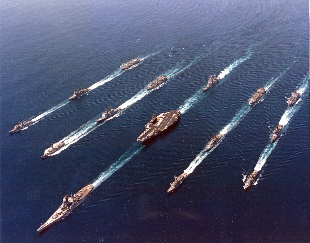 An Iowa class battleship leads a battle group at sea in the 1980s.