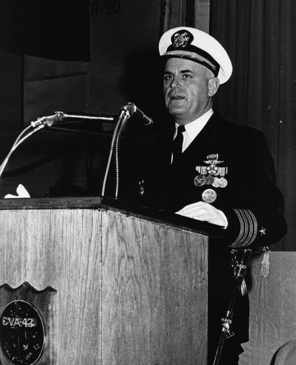 Captain Frank W. Ault reads his new orders during USS Coral Sea's change of command ceremony, 18 March 1967. Captain Ault, after 13 months of outstanding leadership aboard Coral Sea, will report for duty on the staff of Commander Naval Air Forces, US Pacific Fleet with headquarters located in San Diego, California.
