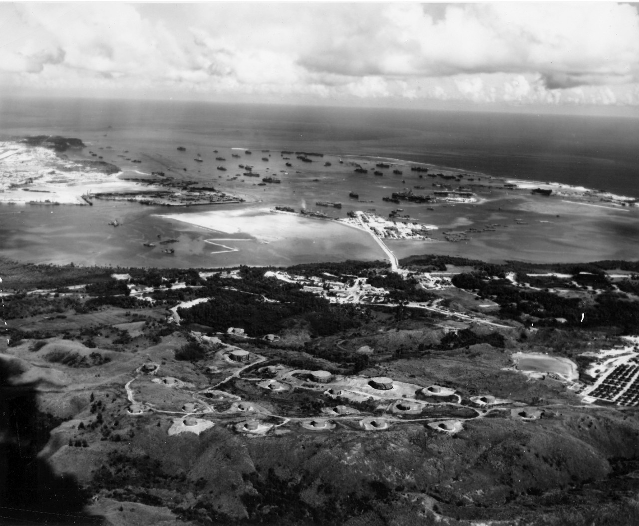 Fuel branch - an aerial view of man-made causeway wehre tankers discharge oil that is pumped into the black oil tank farm shown in the hills. During the eleven months at Guam, 231,167,000 gallons of black oil were issues by the Fuel Branch. October 20, 1945. 