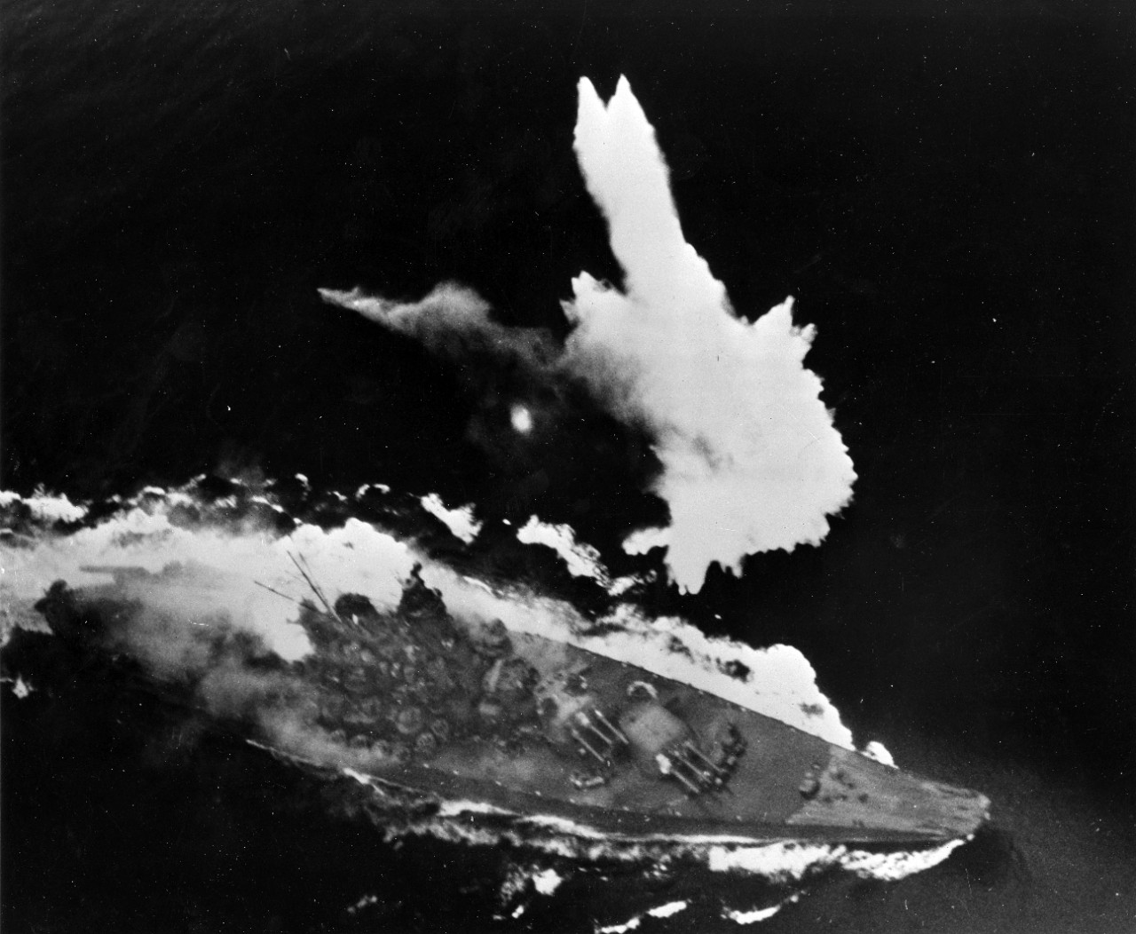 Yamato maneuvers frantically under attack as a bomb explodes off its port side. The fire in the area of the 6.1 inch turret can be clearly seen. 