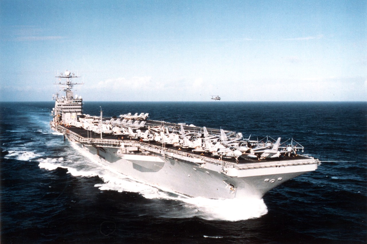 As an SH-60 "Seahawk" from Helicopter Combat Support Squadron Five (HS-5) hovers alongside, the US Navy's aircraft carrier USS George Washington (CVN-73) slices through the waters of the eastern Atlantic Ocean, February 3, 1996. Once on station with commander Sixth Fleet, she will patrol the waters of the Adriatic in support of NATO Peace Keeping Operation Joint Endeavor. 