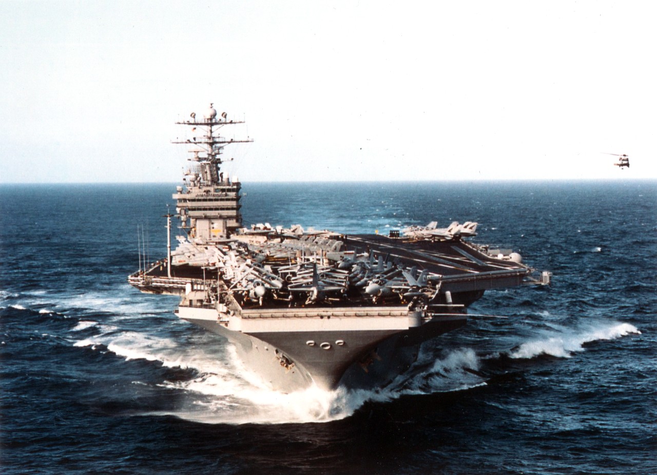 As an SH-60 "Seahawk" from Helicopter Combat Support Squadron Five (HS-5) hovers alongside, the US Navy's aircraft carrier USS George Washington (CVN-73) slices through the waters of the eastern Atlantic Ocean, February 3, 1996. Once on station with commander Sixth Fleet, she will patrol the waters of the Adriatic in support of NATO Peace Keeping Operation Joint Endeavor.
