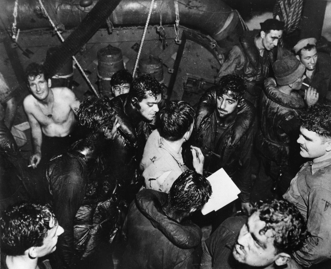 Covered with oil of their torpedoed ship, USS Helena (CL-50), survivors respond to a roll call aboard the destroyer which picked them up. Three times the destroyer had to leave off its rescue work to do battle with Japanese warships.