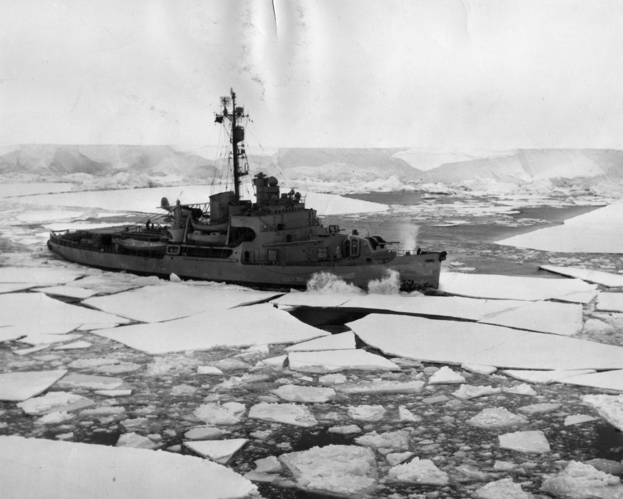 Icebreaker USS Northwind (AGB-5) cuts across the bow of USS Mount Olympus (AGC-8) to clear a path for her, through pack ice off Ross Sea, Antarctica