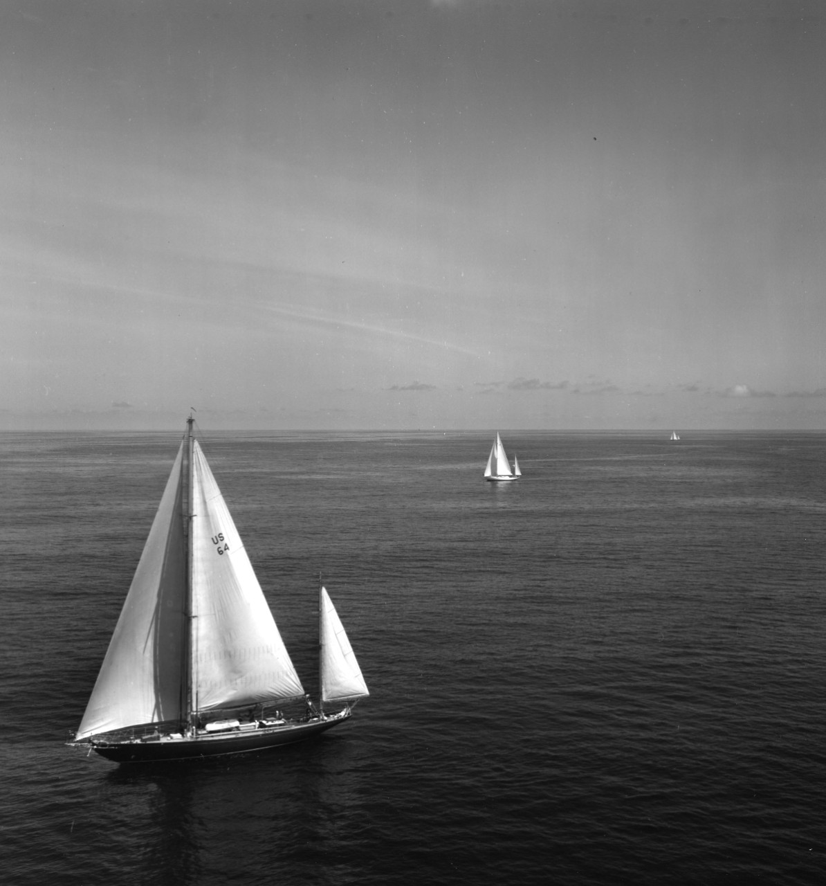 Auxiliary yawl USS Royono (IX-235) under sail during a Bermuda yacht race. Yacht Enchanta can be seen in in center background.