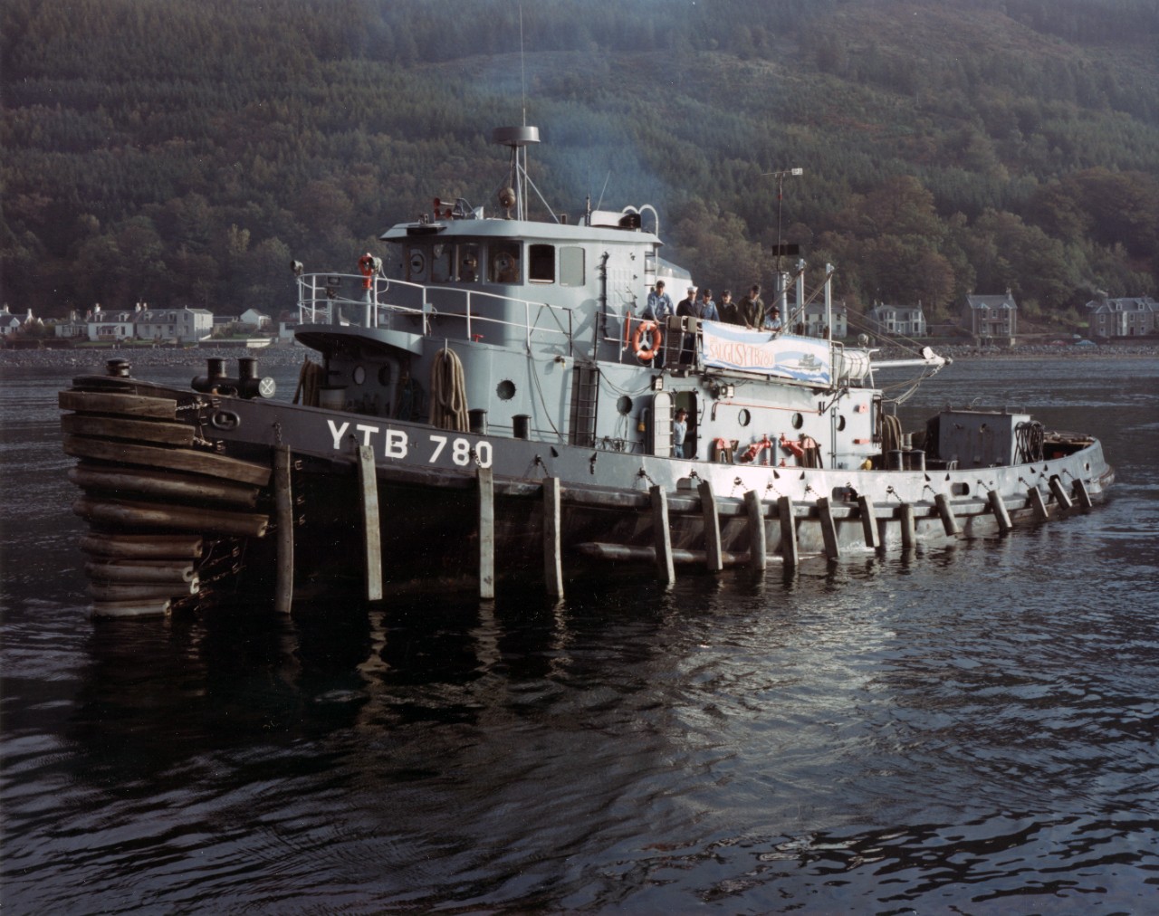 Natick-class large harbor tug Saugus (YTB-780) at Holy Loch, Scotland, circa early 1990s. Note that the tug's crew is assembled on deck.