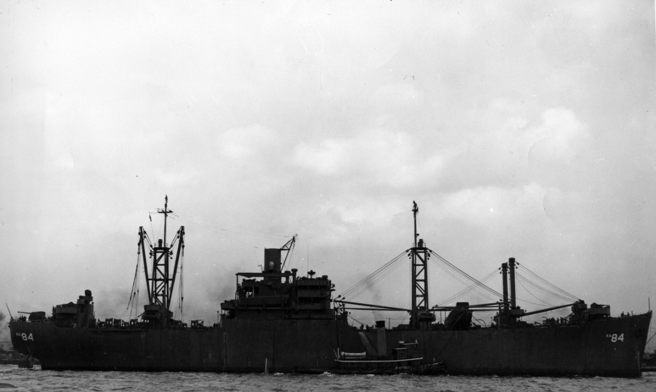 Starboard broadside view of attack cargo ship USS Waukesha (AKA-84) being assisted by a tugboat