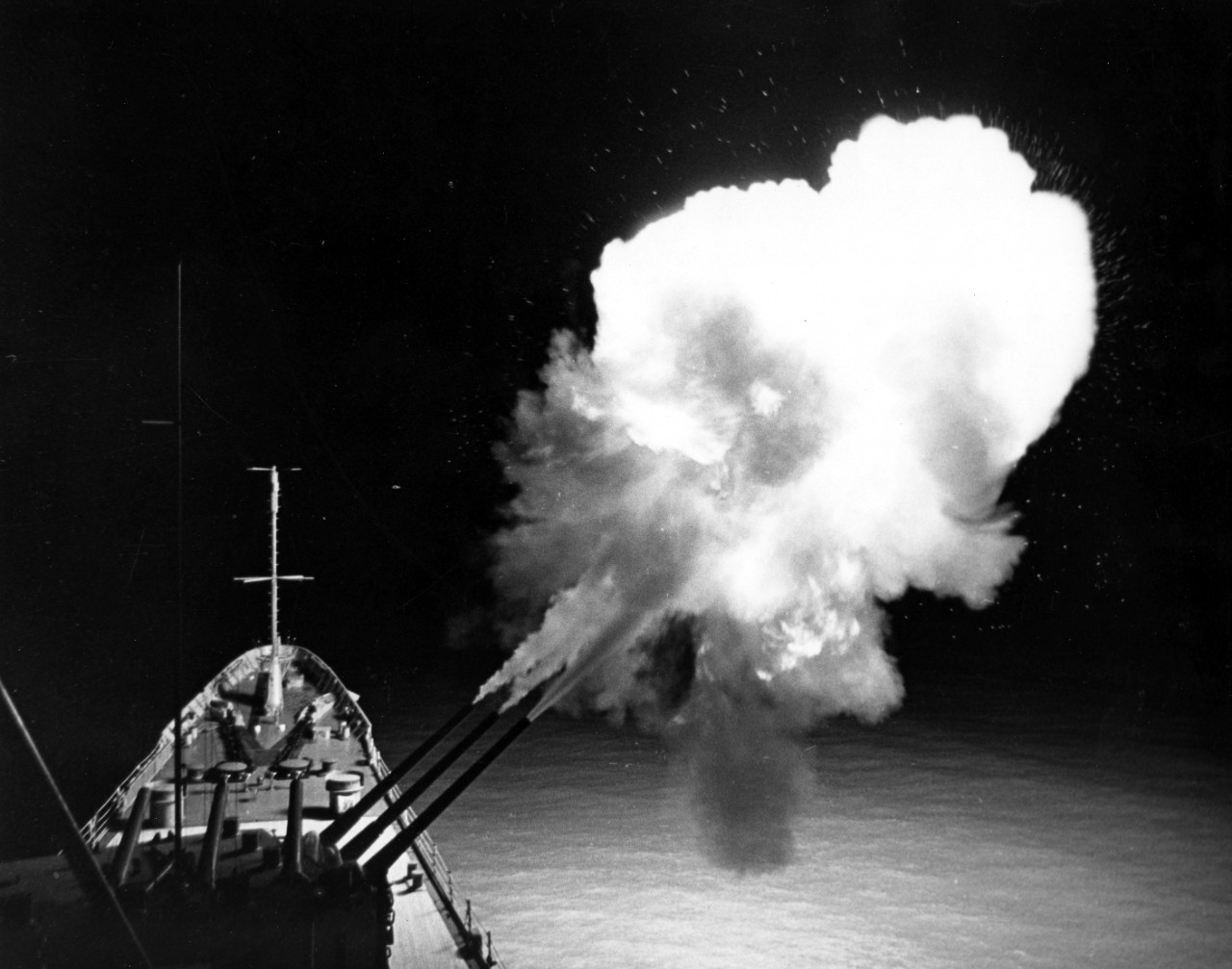 A ball of fire lights up USS Canberra (CAG-2) as three gun salvo is fired toward North Vietnamese targets, March 1967. 