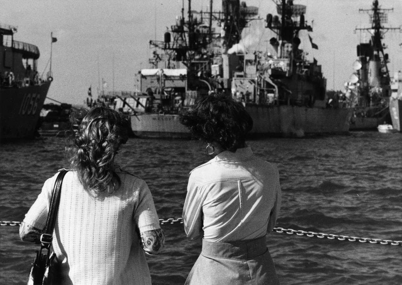 Two Navy family members gaze out on moored ships, including USS McCloy (FF-1038) and USS Conole (FF-1056)