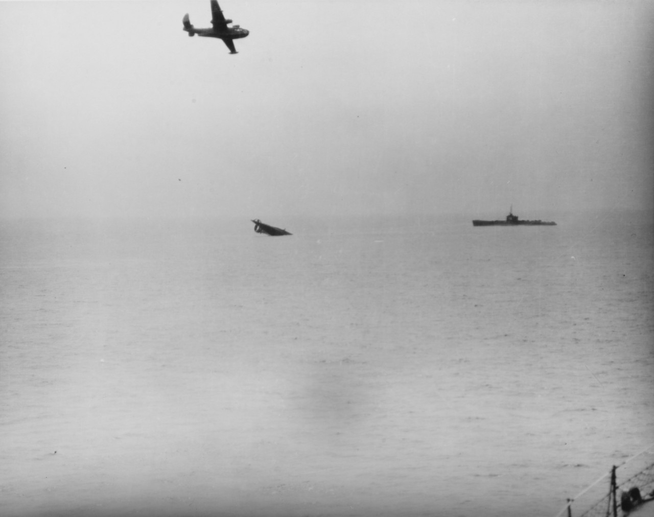 Sinking of a Japanese "I-boat" submarine, during mass scuttling of Japanese subs off Sasebo, 1 April 1946. Another submarine is awaiting sinking, as a PBM flies overhead.