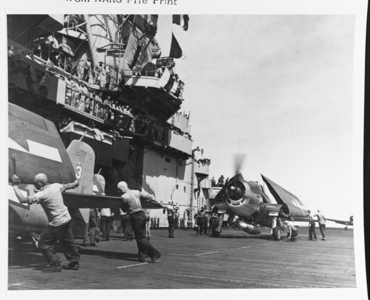black and white photograph showing men aiding aircraft on the flight deck of USS Essex during WWII. 