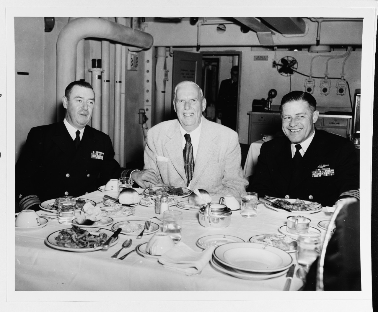 Rear Admiral Francis X. McInerney, USN, an unidentified civilian, and Captain William P. Burford