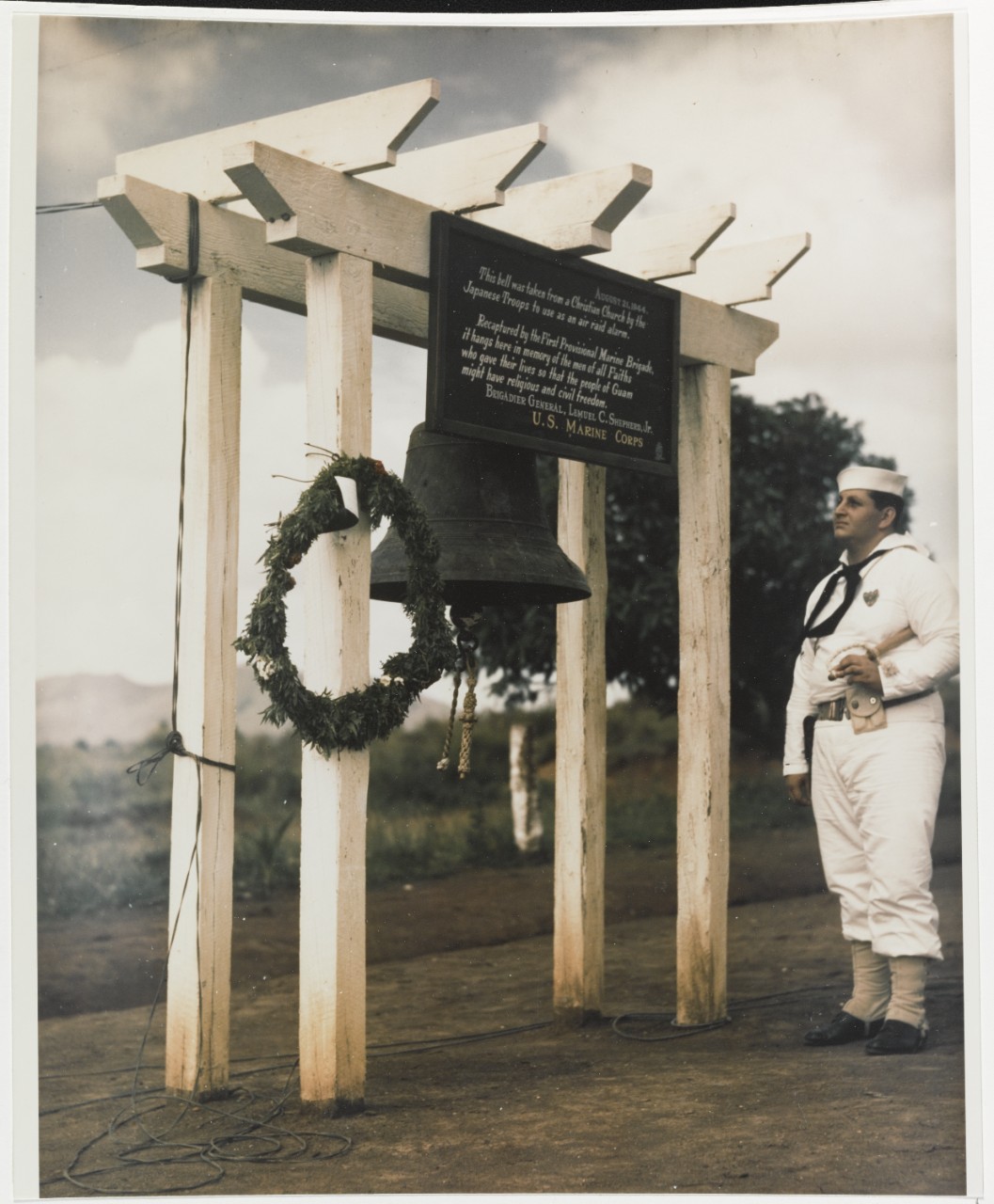 Agat Cemetery, Guam. Cox. Mike F. Venute, USN, stands beside the cemetery bell, 30 May 1945
