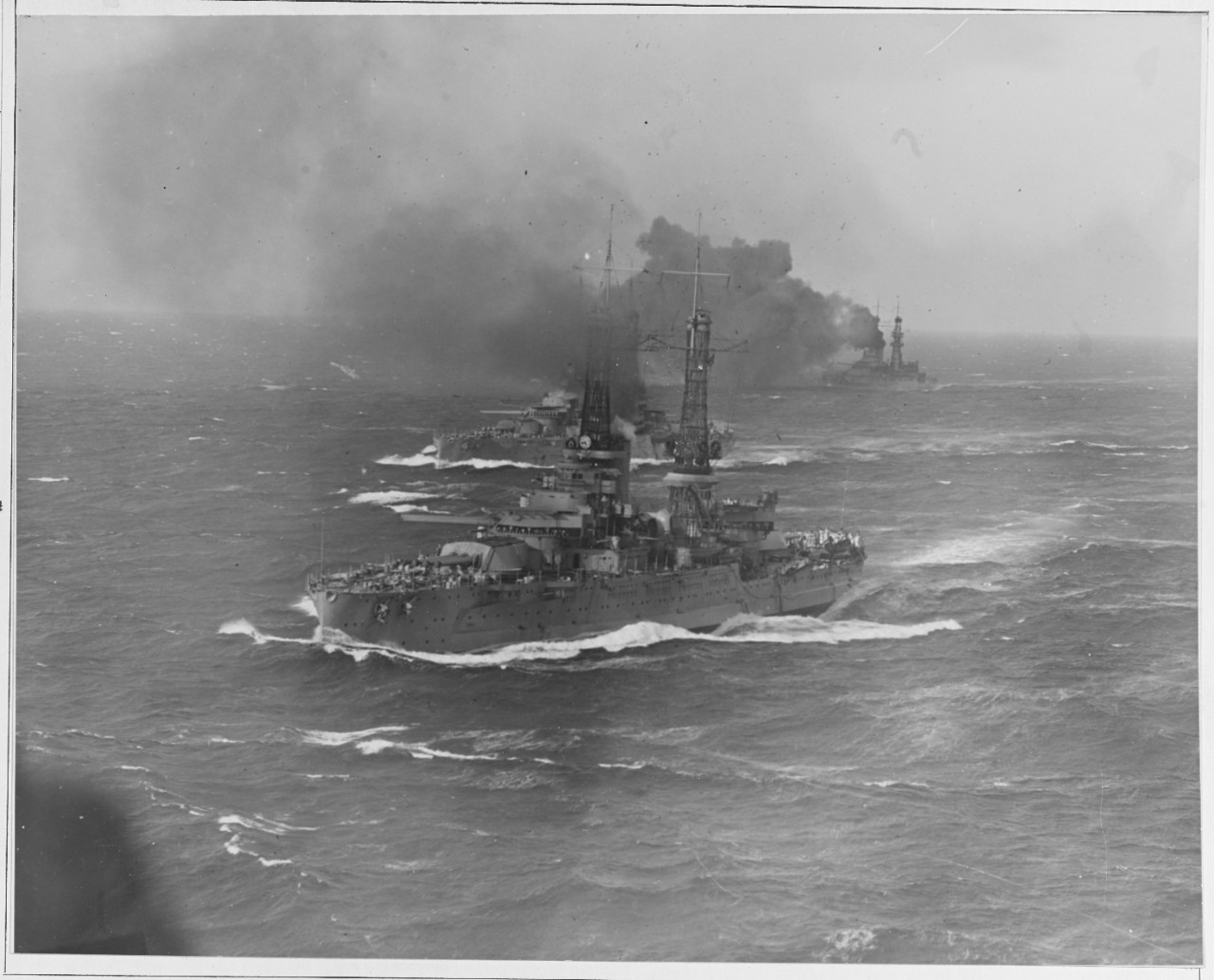 Three-quarter bow view of battleship squadron operating at sea in 1921.