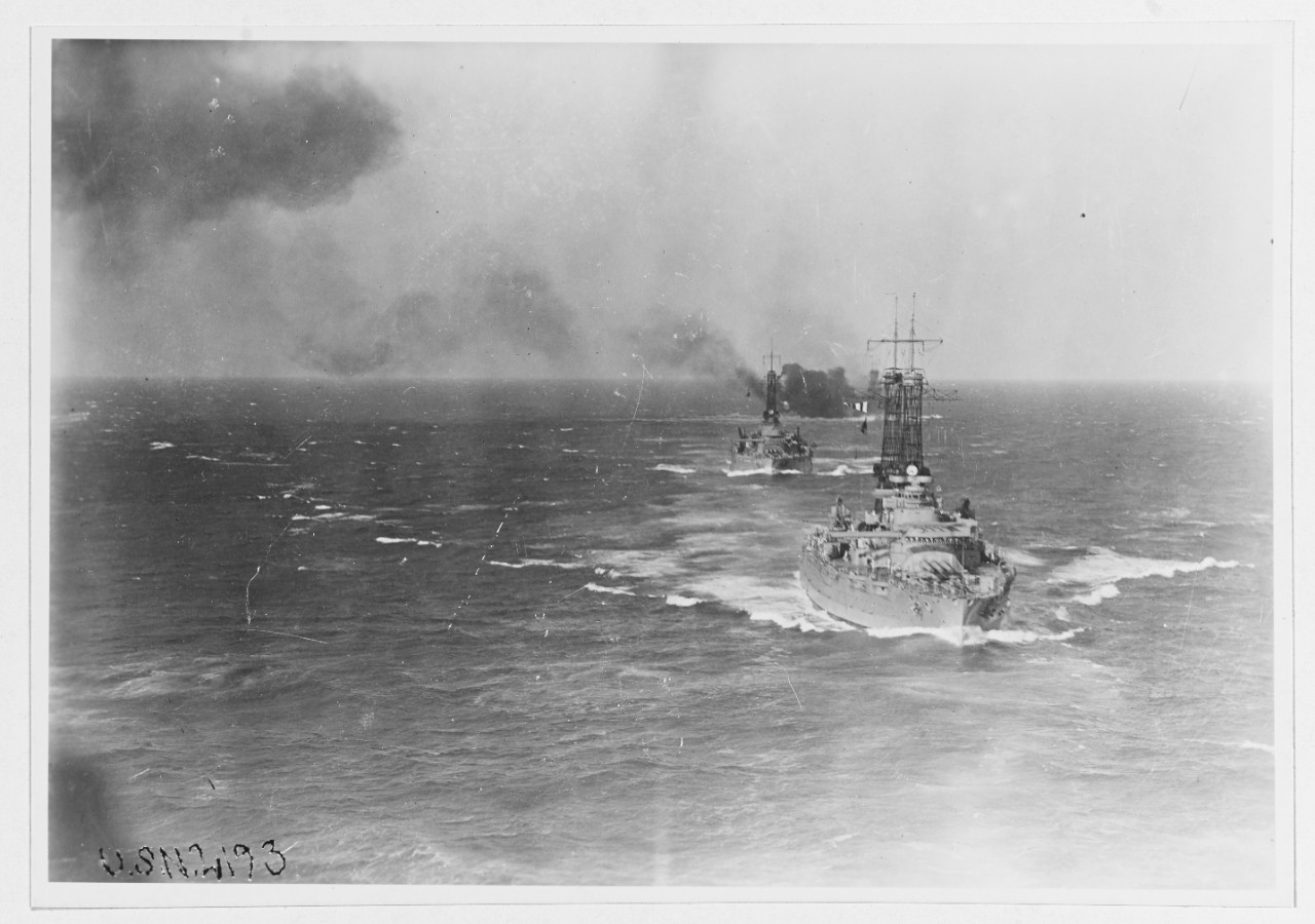 Starboard three-quarter bow view of battleships steaming in 1921.
