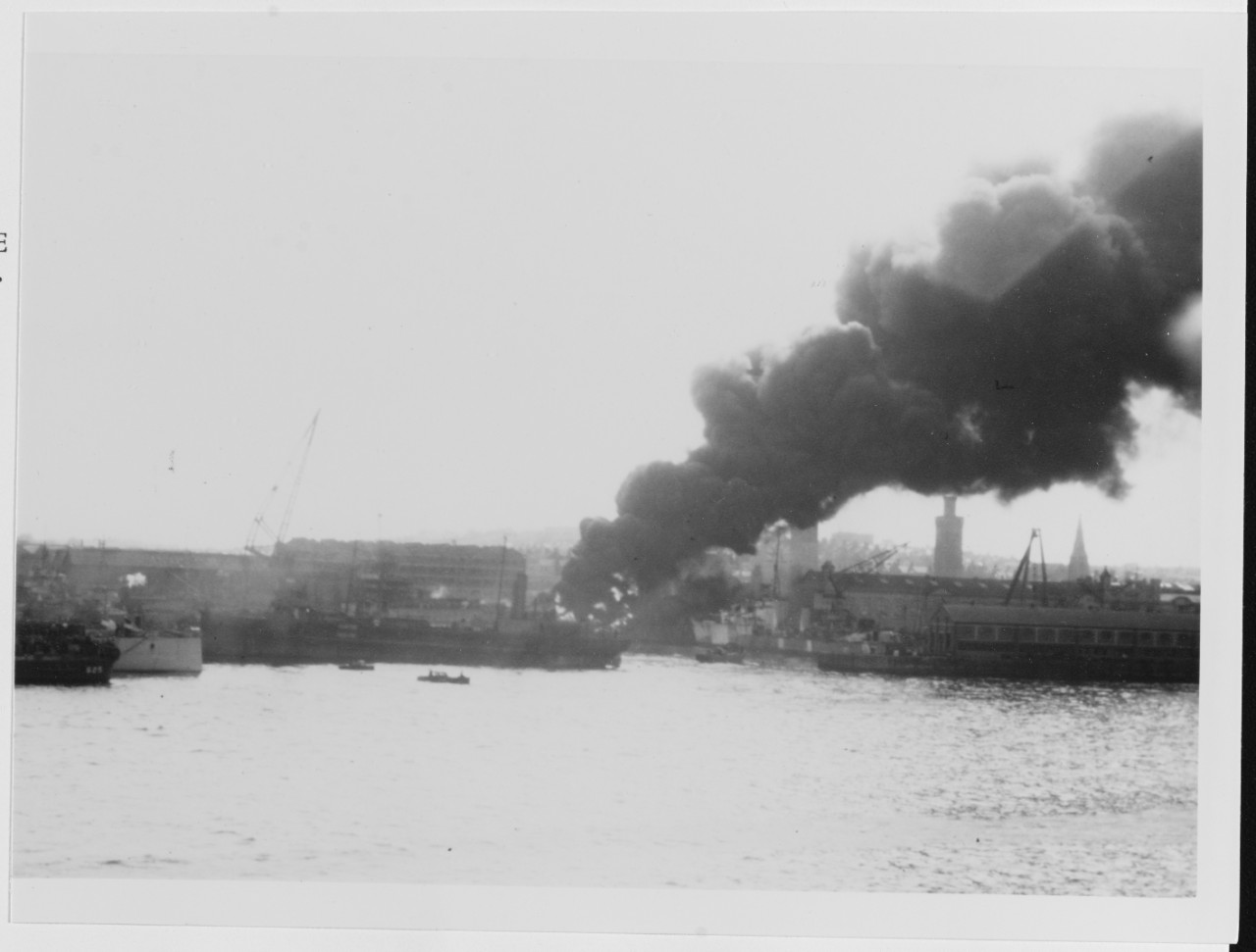 Plymouth, England. Fire from a bomb hit at a British Submarine Yard, circa Spring 1945. Stern of USS HARDING (DD-625)