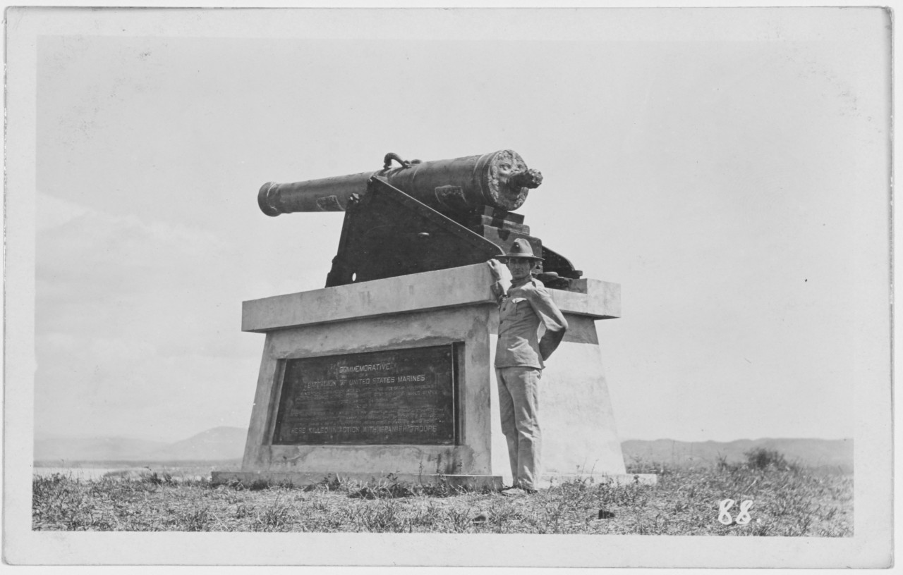 Marine poses by the monument of capture of Guantanamo by a Marine Battalion, circa 1909