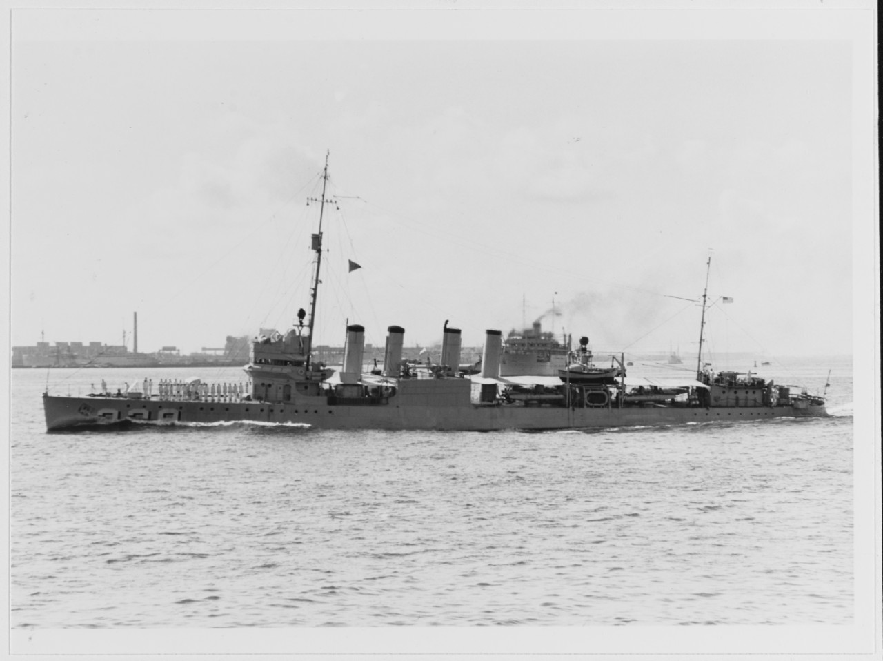USS TRUXTUN (DD-229) steaming in harbor, with sailors paraded by her forecastle gun, during the 1930s