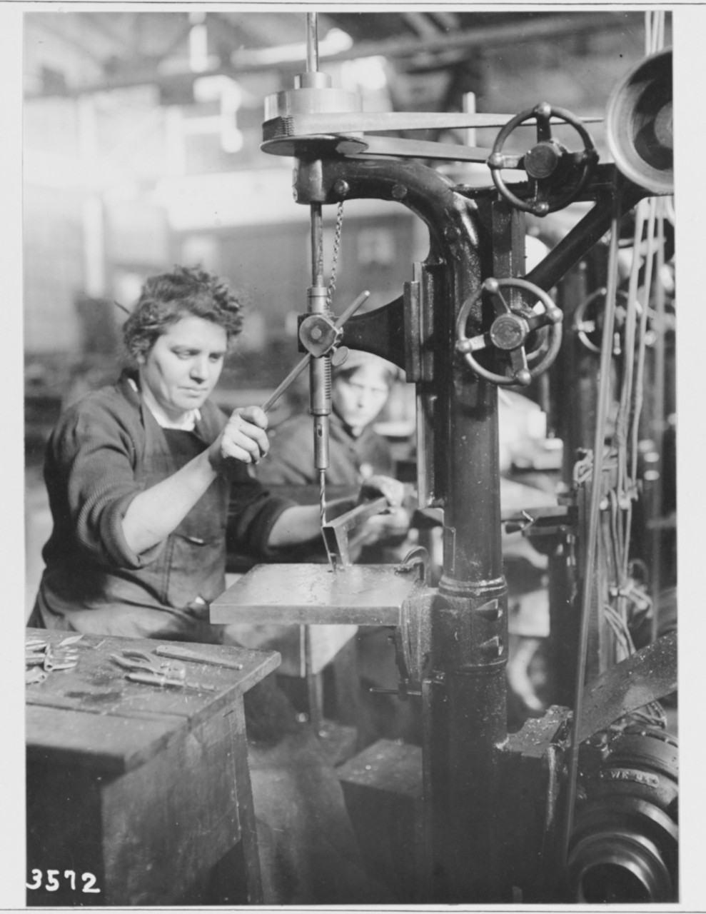 Women workers running drill press