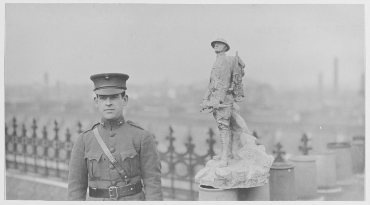 Man in uniform stands next to a Statue of a Marine in France