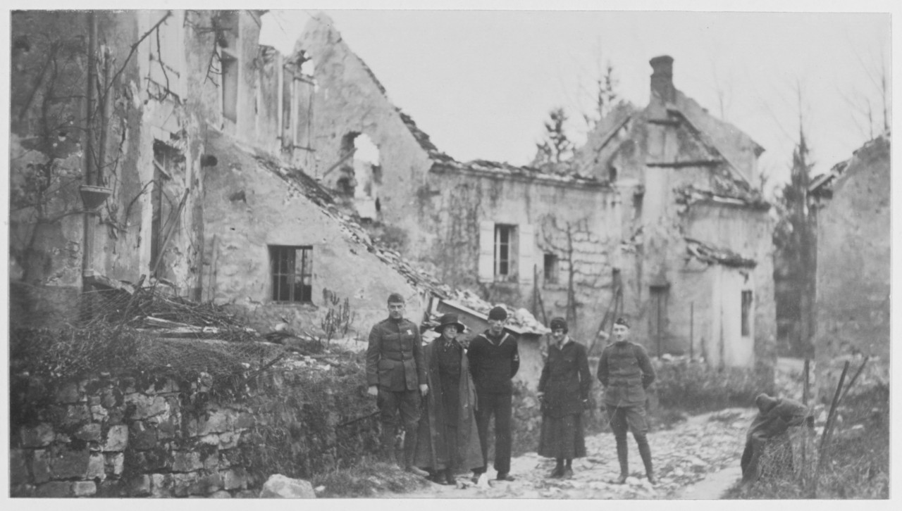 Marines, sailor and two women stand in front of ruins of Chateau Theirry in France, during World War I.