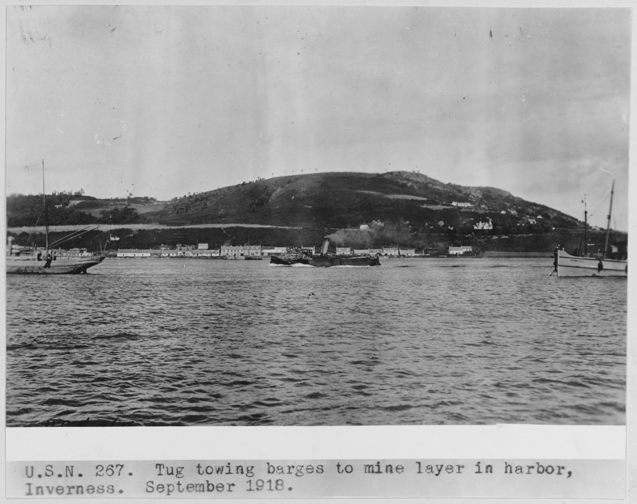 Tug towing barges to mine layer in harbor, Inverness, Scotland. September 1918. USN 267