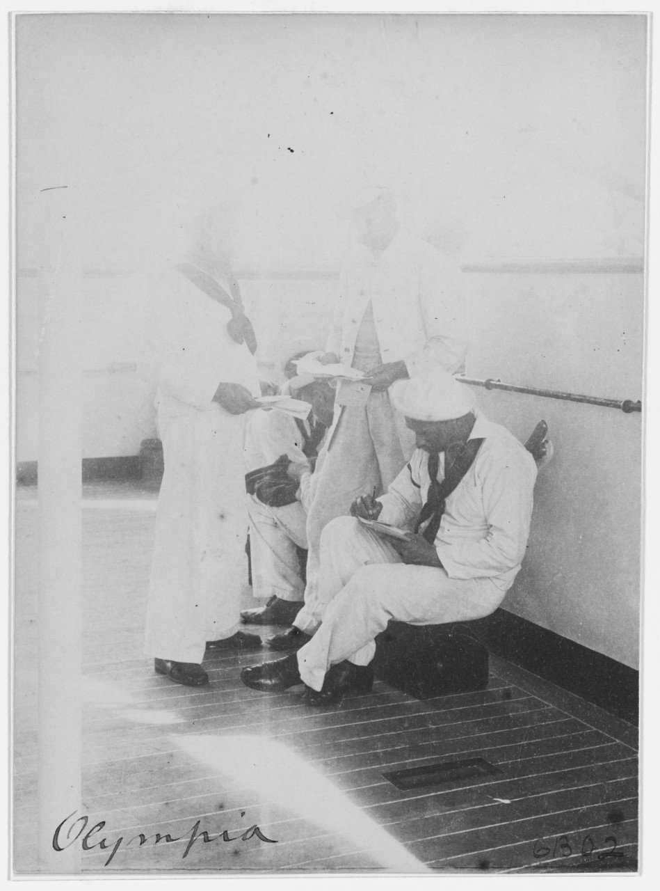 USS OLYMPIA (C-6), enlisted crewmen reading and writing letters, 1898. 