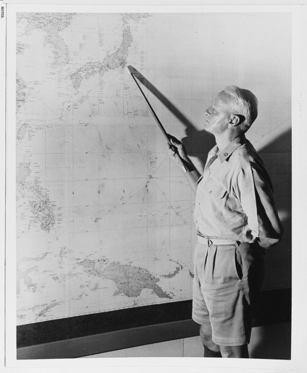 Fleet Admiral Chester W. Nimitz, USN (CinCPac-POA), points to Tokyo, Japan, on a wall map.