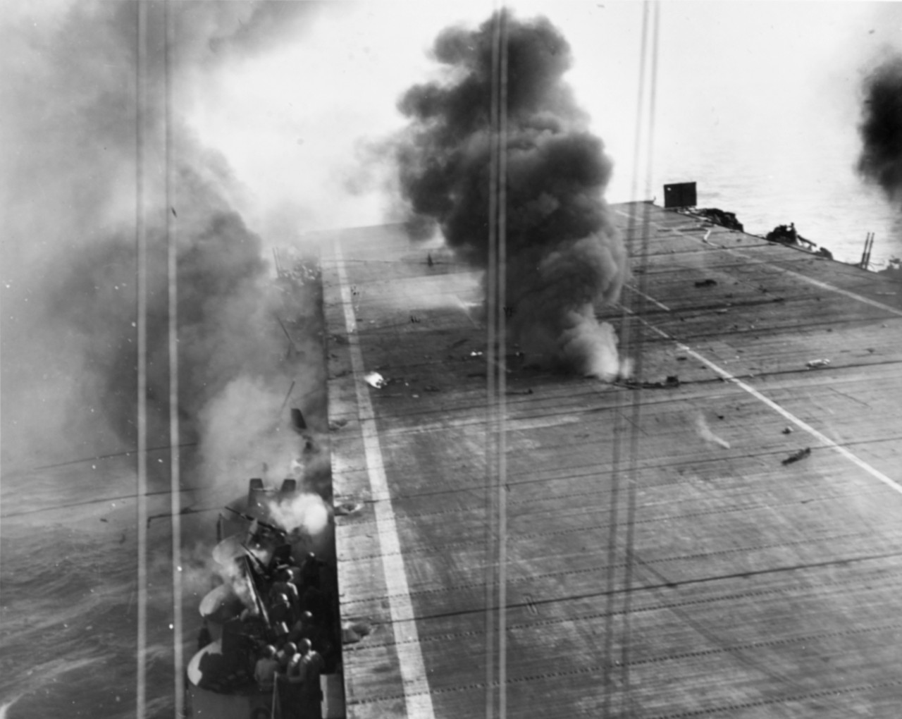 Effect of crash dive on Suwannee flight deck. 25o kilogram bomb has just exploded between flight and hangar decks and fire billows out, 25 October 1944.