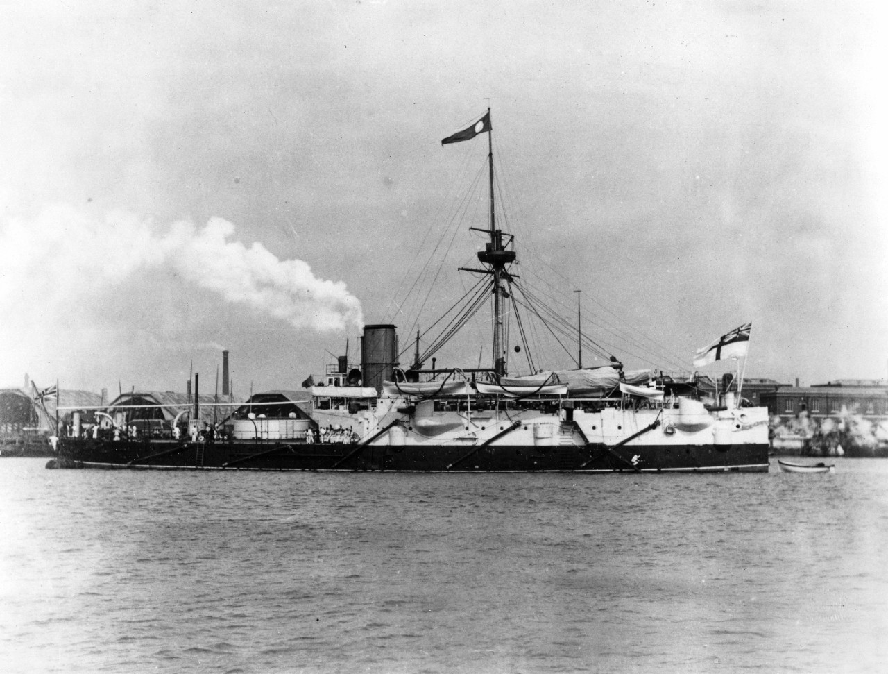 Hero, British Coast Defense Battleship (1885-1908), probably photographed at Portsmouth where she served as a gunnery school ship from 1889 to 1902. The pennant at the masthead may be for identification in one of the maneuver "fleets." Note the covered shiphouses in the background for new ship construction.