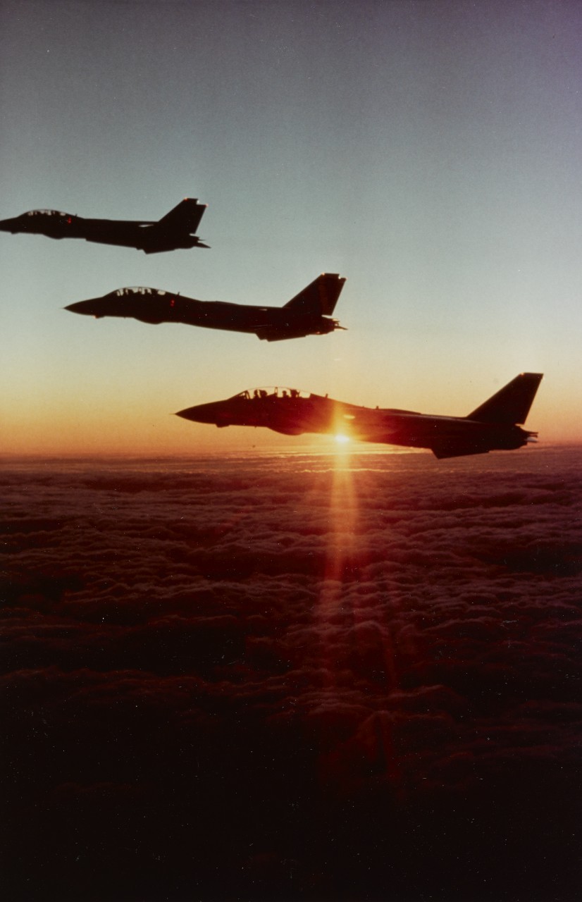 Three F-14A "TOMCAT" Fighters fly in formation over a field of heavy clouds, at sunset, September 25, 1980