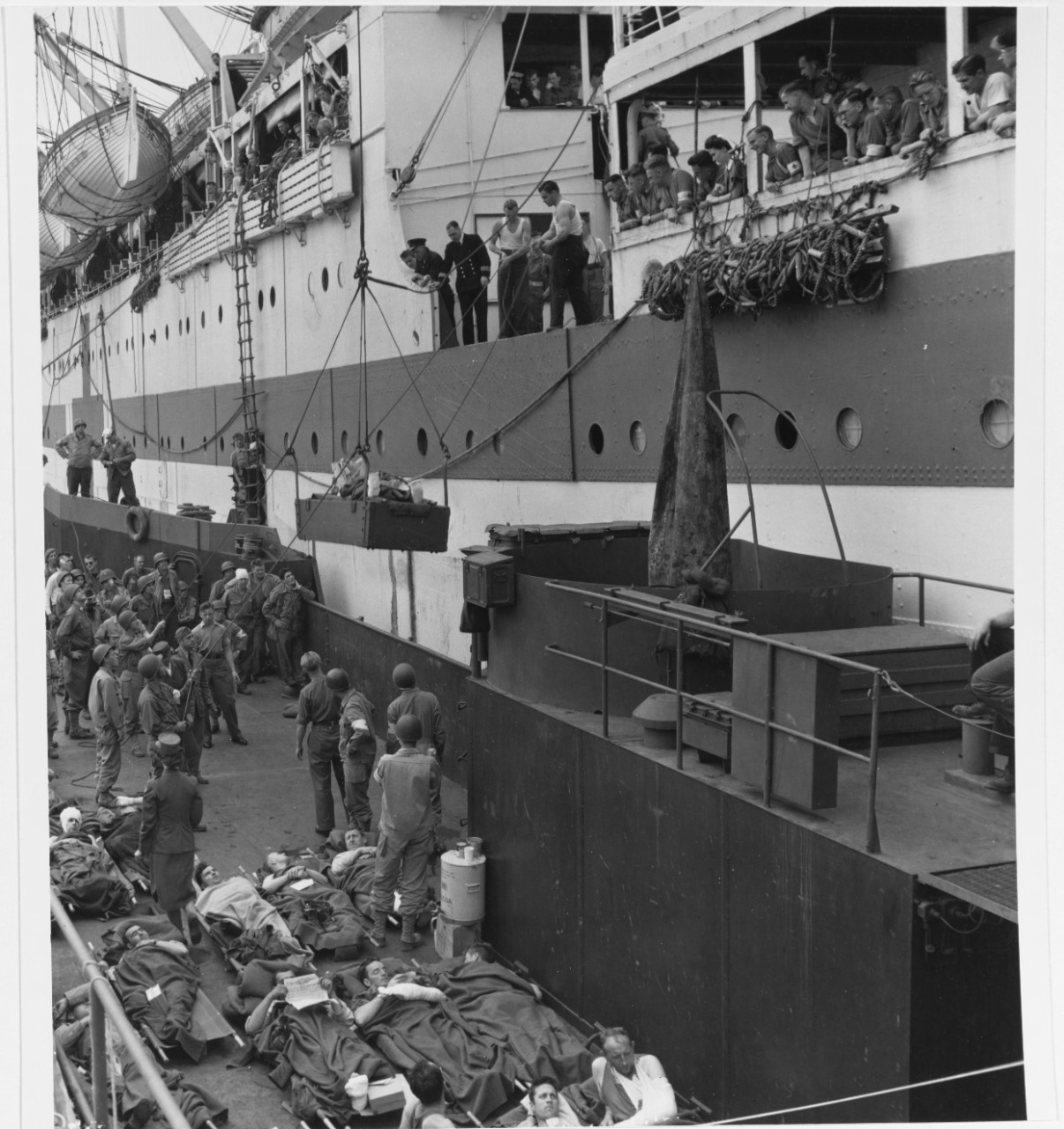 Casualty Evacuation. Wounded Americans are hoisted aboard a British Hospital Ship from an LCT, en route to Britain from the combat zone in Northern France, 7 August 1944.