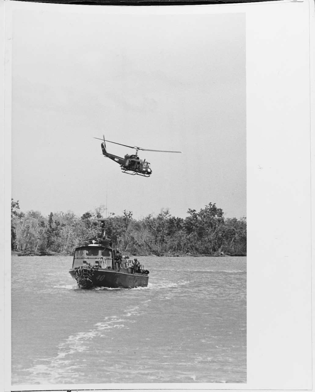 A UH-1 Iroquois helicopter flies near an inshore PCF on the Cualon River.