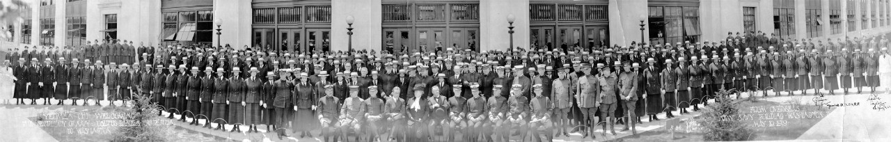 Oversized panoramic photograph: New Navy building (Main Navy building) with Navy and Marine Corps staffs (mostly female Yeomen) welcoming Secretary of the Navy Josephus Daniels on his return to Washington from overseas at the new Navy Building, Washington, D.C., May 19, 1919; image also features Assistant Secretary of the Navy Franklin D. Roosevelt seated two seats to Daniels' right, 1919. 