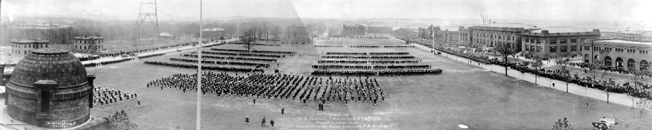 Oversize panoramic view of parade ground with trainees on parade at Naval Training Station Great Lakes, IL, ca. 1918. Commandant is RADM F.B. Bassett.