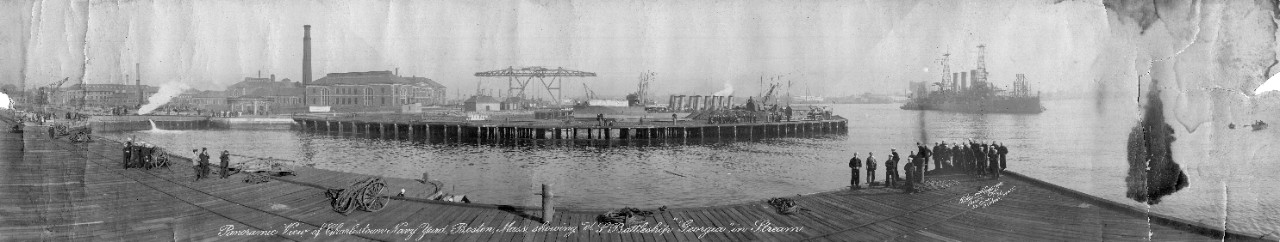 View of Boston Navy Yard, MA, looking along the waterfront, ca. pre-World War I. USS Georgia (BB-15) is offshore.