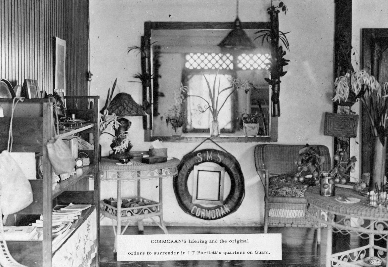 SMS Cormoran Life Ring hanging on the wall of Lieutenant Bartlett's quarters at Guam, circa World War I. Original orders to surrender the ship are framed inside the life ring, but illegible in this photo.