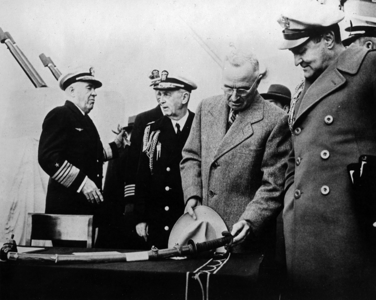 President Harry S. Truman reviews a Japanese sword on the USS Missouri (BB-63) surrender table. Present: (left to right): Admiral Jonas H. Ingram, USN; Fleet Admiral William D. Leahy, USN, (the President's Chief of Staff); President Harry S. Truman; and Brigadier General Vaughn, USA. Original photo from collection S-423.