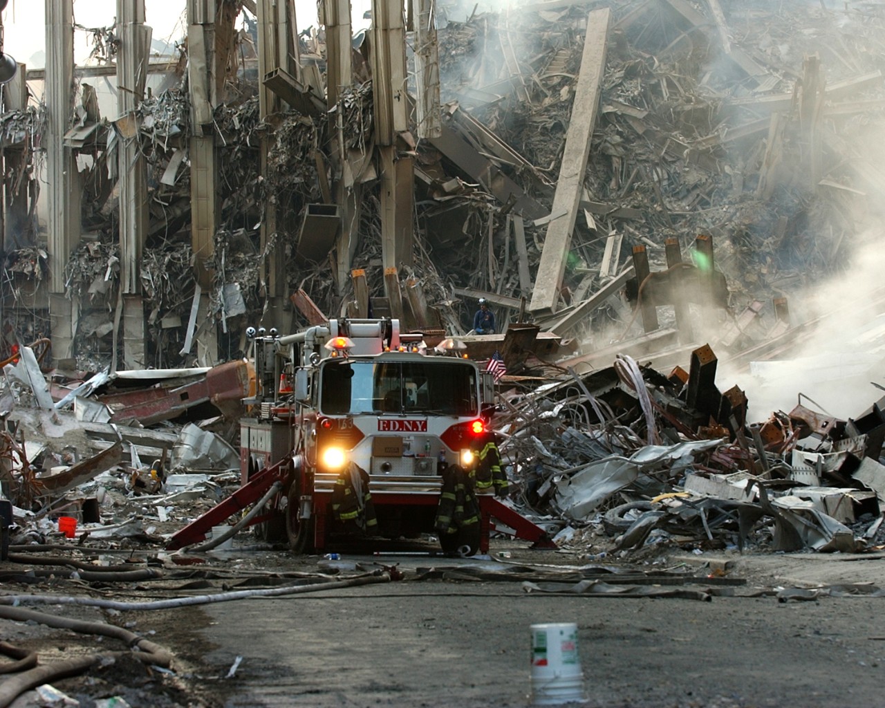 A lone fire engine sits amid the smoldering rubble of the World Trade Center while search and rescue operations continue, 16 September 2001