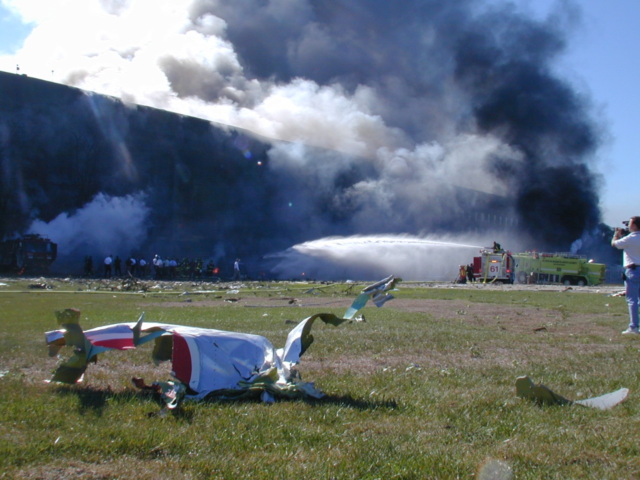 A piece of aircraft lies in the grass while fire crews work to put out the flames in the minutes after the attack, 11 September 2001