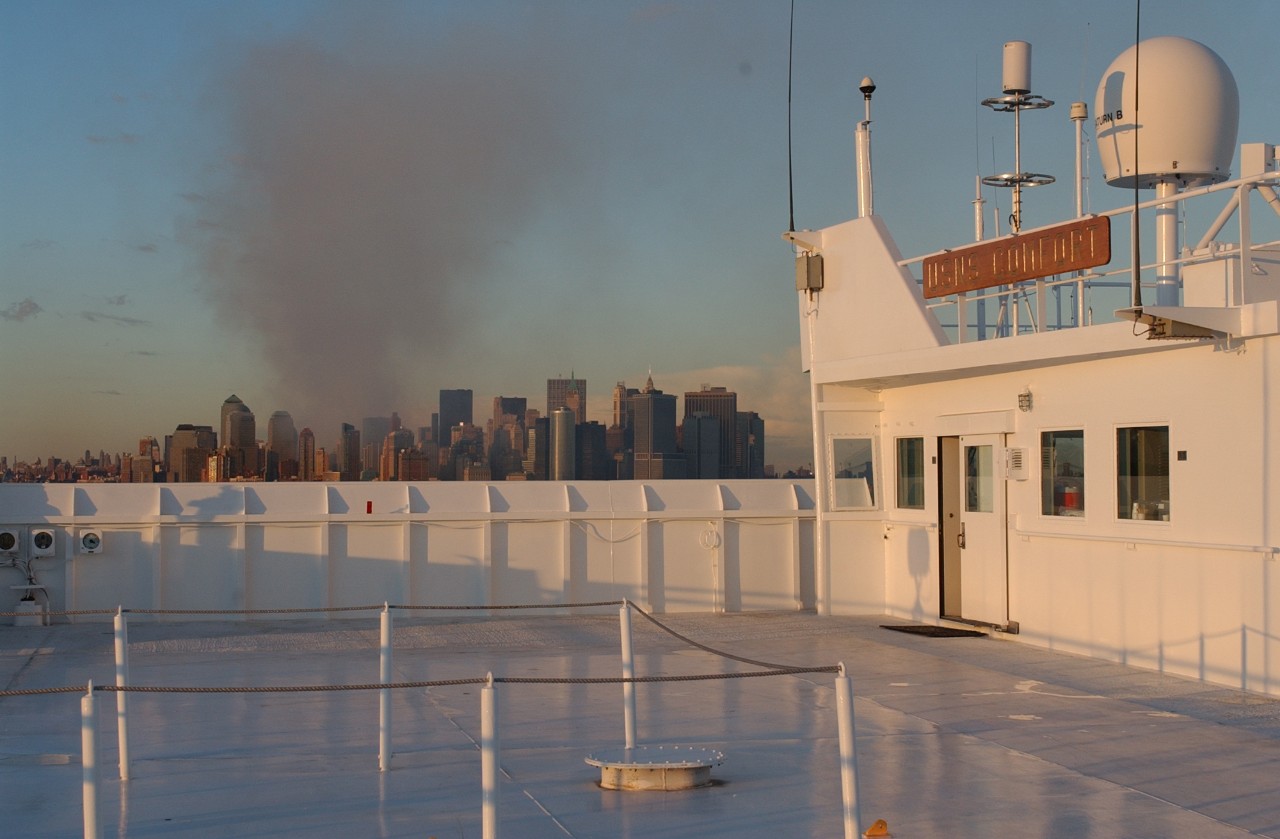 Smoke rises from Lower Manhattan as USNS COMFORT (T-AH 20) sails into New York Harbor on 14 September 2001