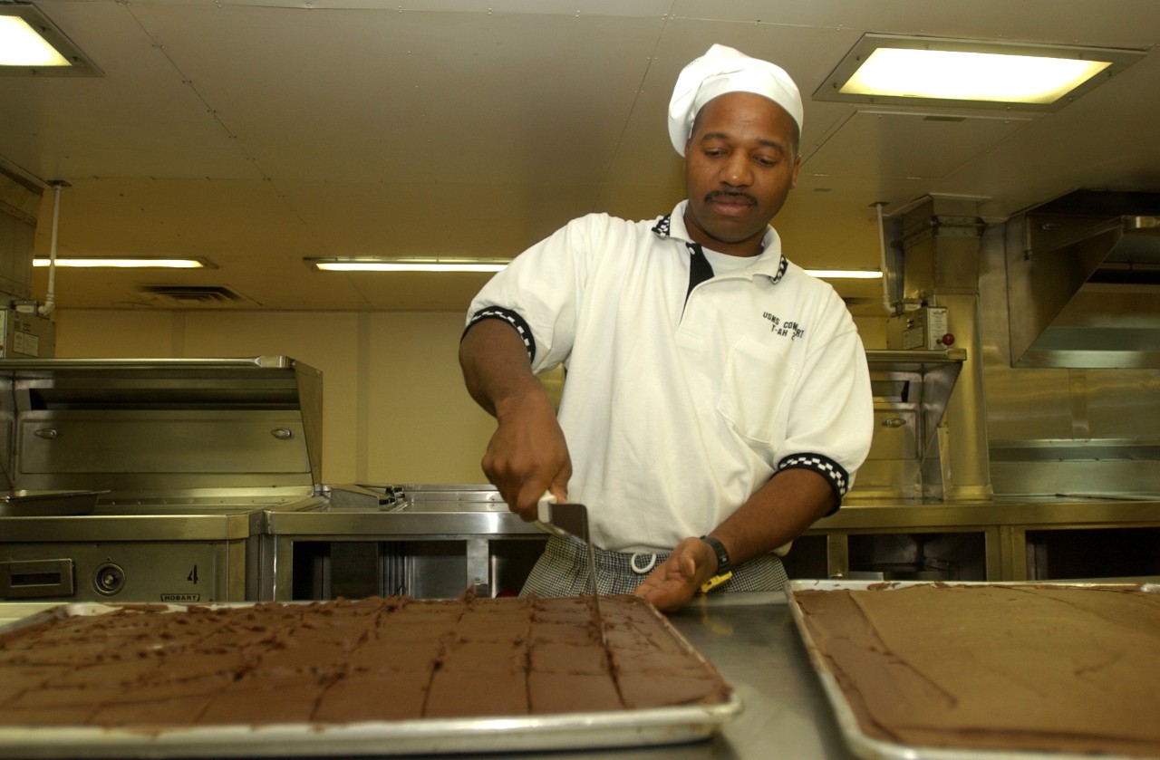 A Petty Officer aboard USNS COMFORT (T-AH 20) prepares dessert for an afternoon meal for firemen, policemen, and volunteers who are working at Ground Zero in New York City, 19 September 2001