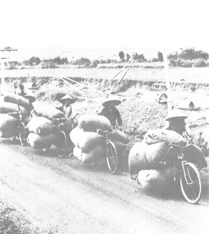 Image of North Vietnamese Transporting 500 Pound Loads of Rice on Bicycles over Unimproved Roads